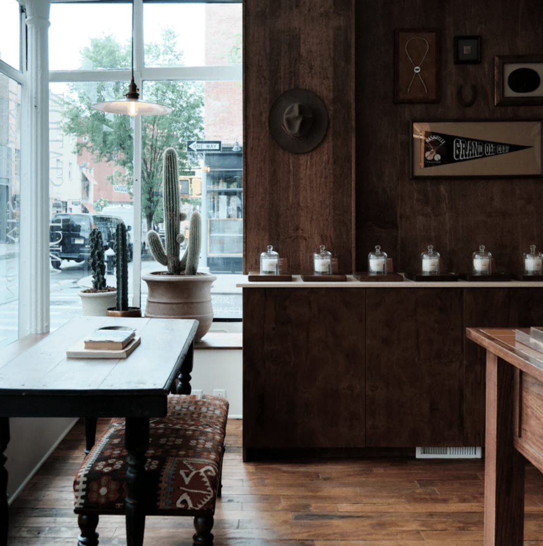 The Ranger Station West Village house — a corner window onto Bleecker Street with cacti, a felt hat and a Grand Ole Opry pennant on the wood-paneled wall.