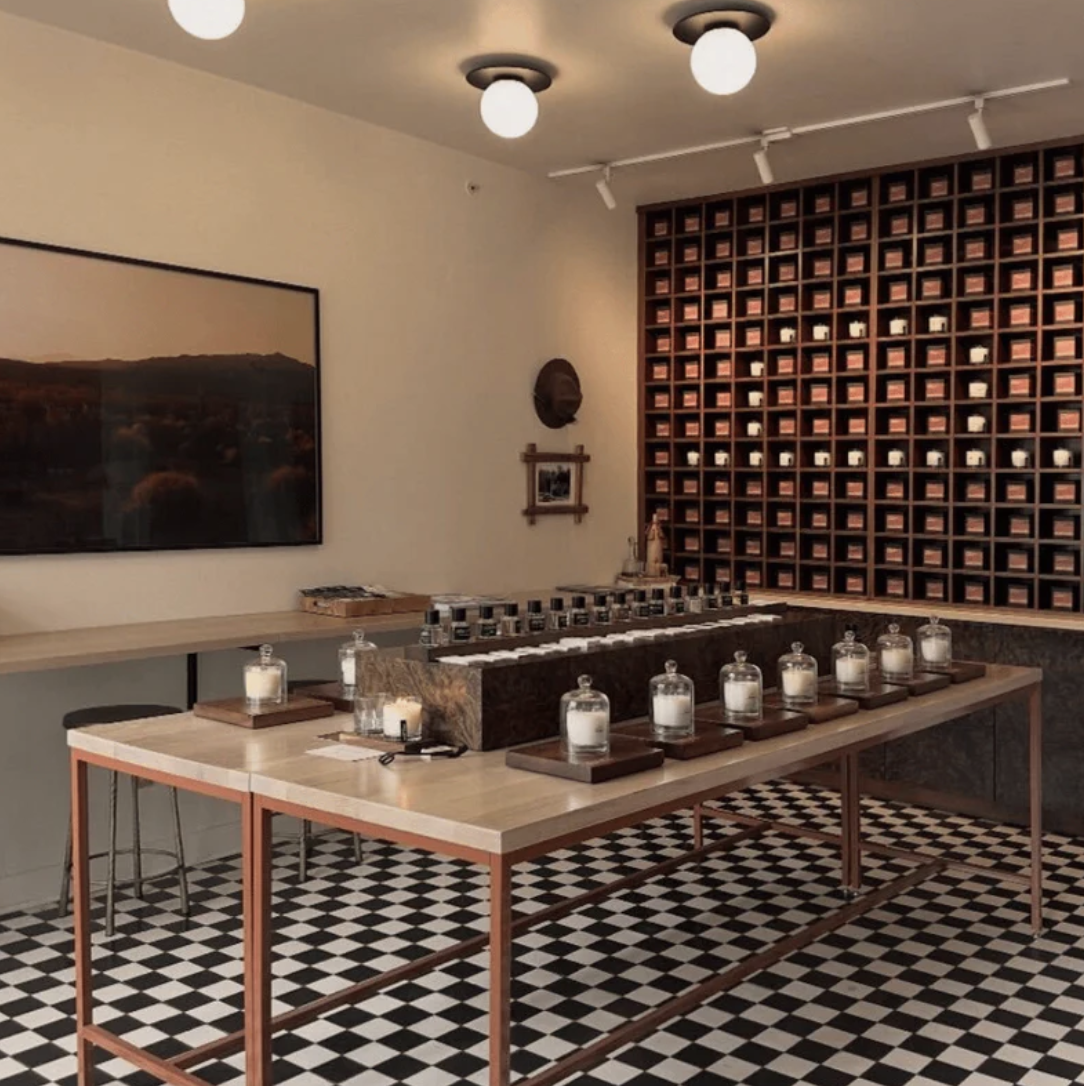 The Ranger Station 12 South house — a floor-to-ceiling grid of candle boxes behind a long testing table on checkerboard tile.