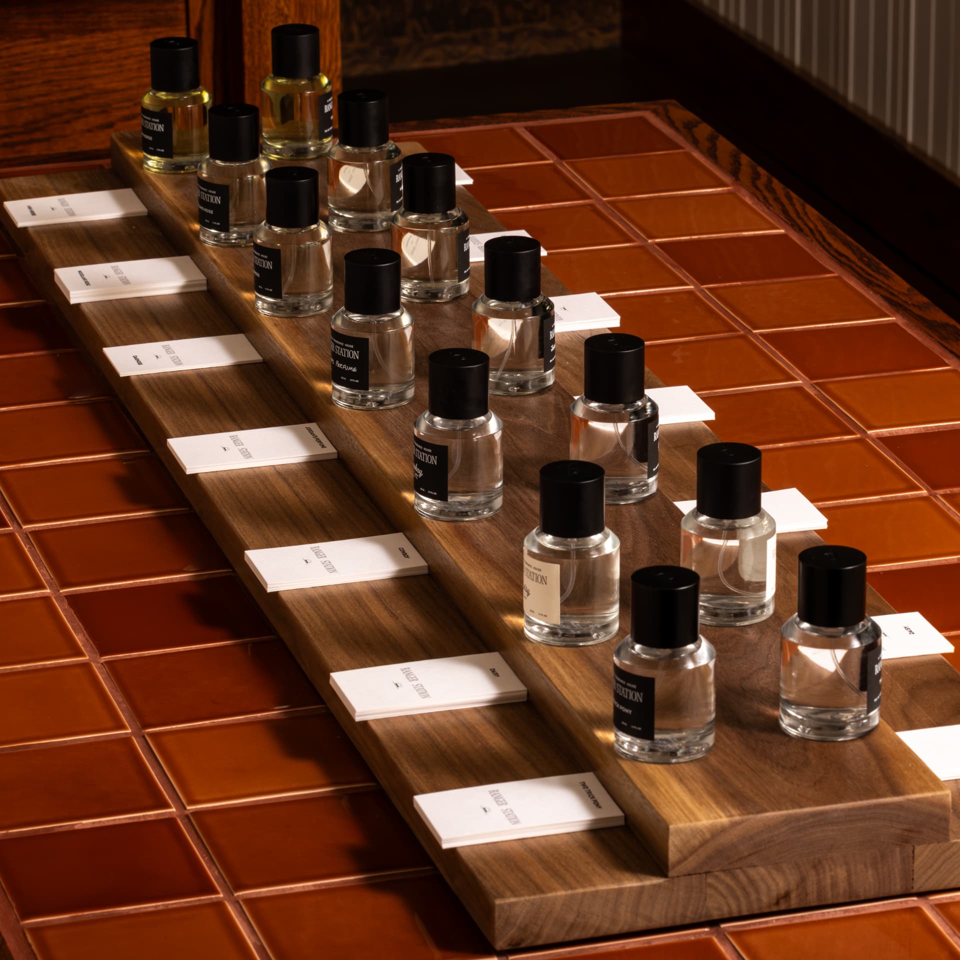 Ranger Station perfume bottles arranged on a walnut board over rust-glazed tile.